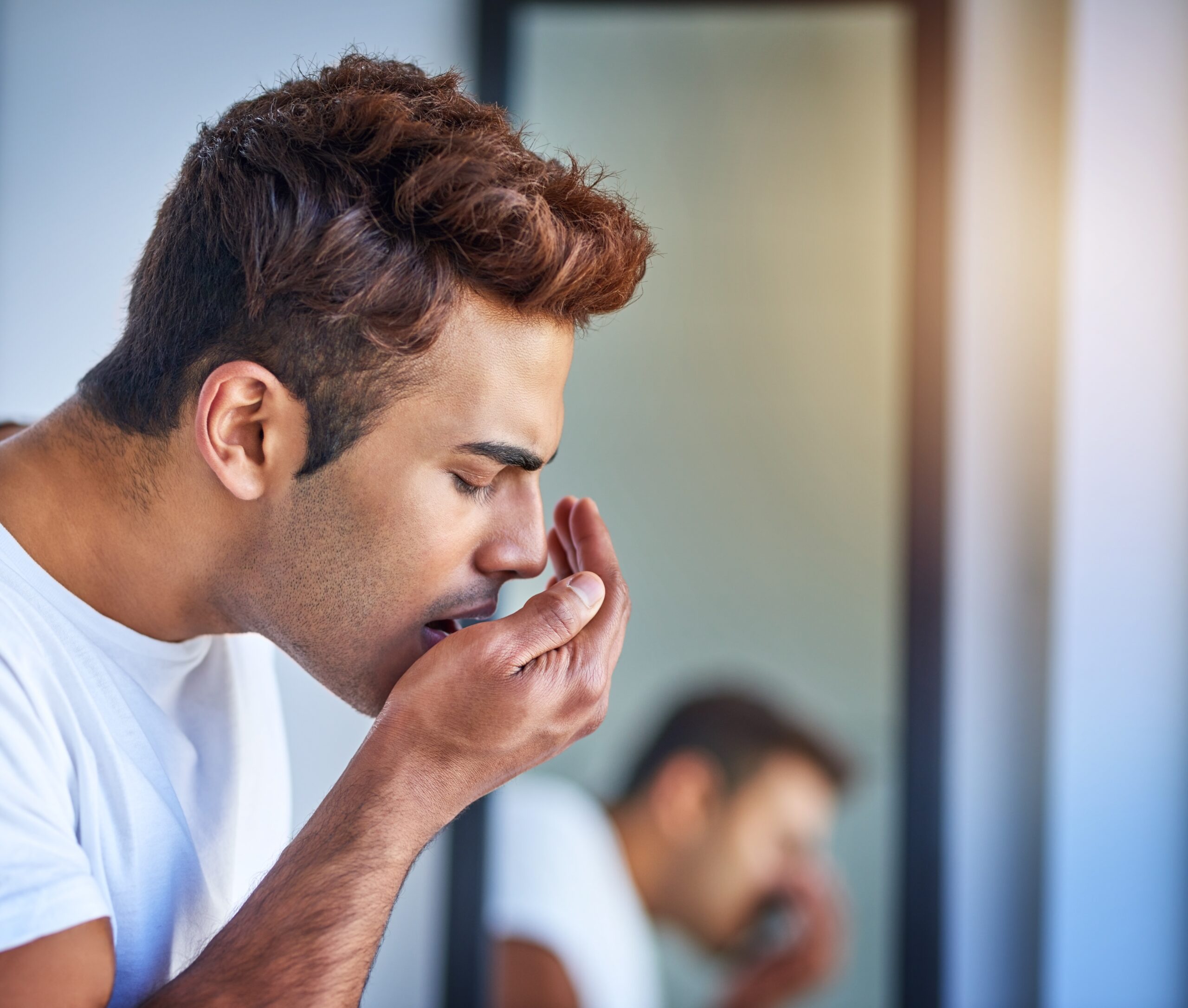 man checking for bad breath in bathroom, morning routine for halitosis problem