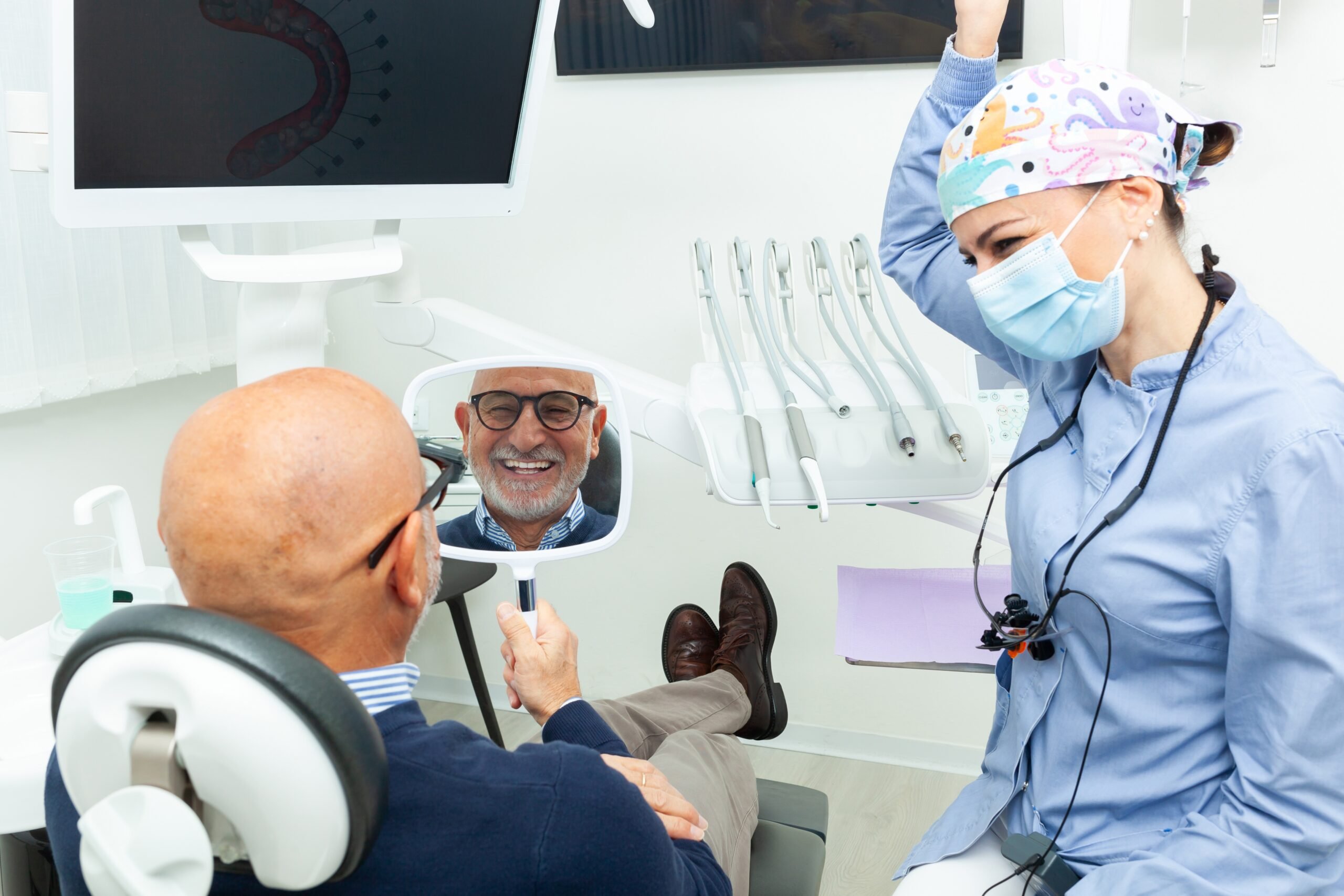 man smiling in a mirror looking at his new dentures in Los Angeles