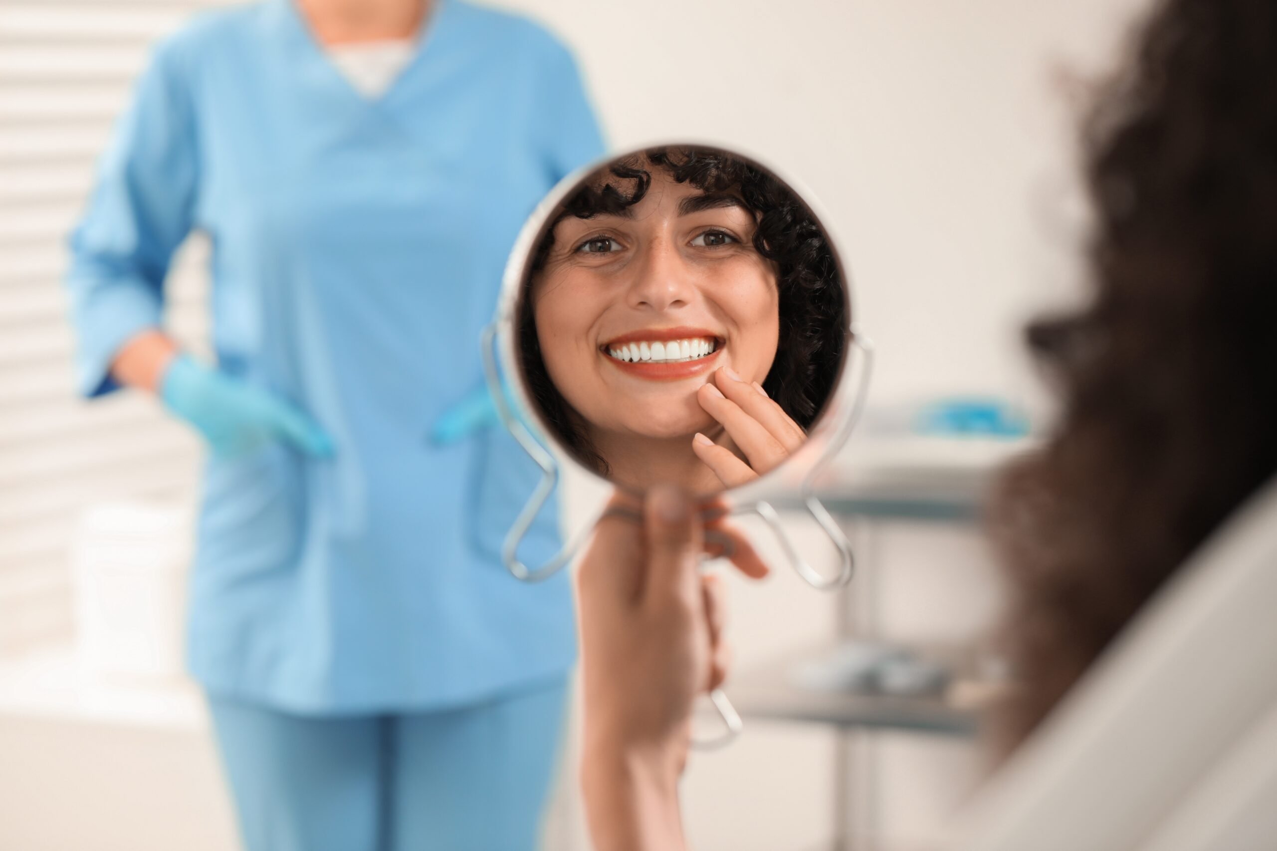 woman smiling in mirror, happy with newly bonded teeth