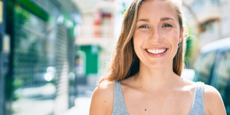 Young blonde woman smiling happy walking the streets of city
