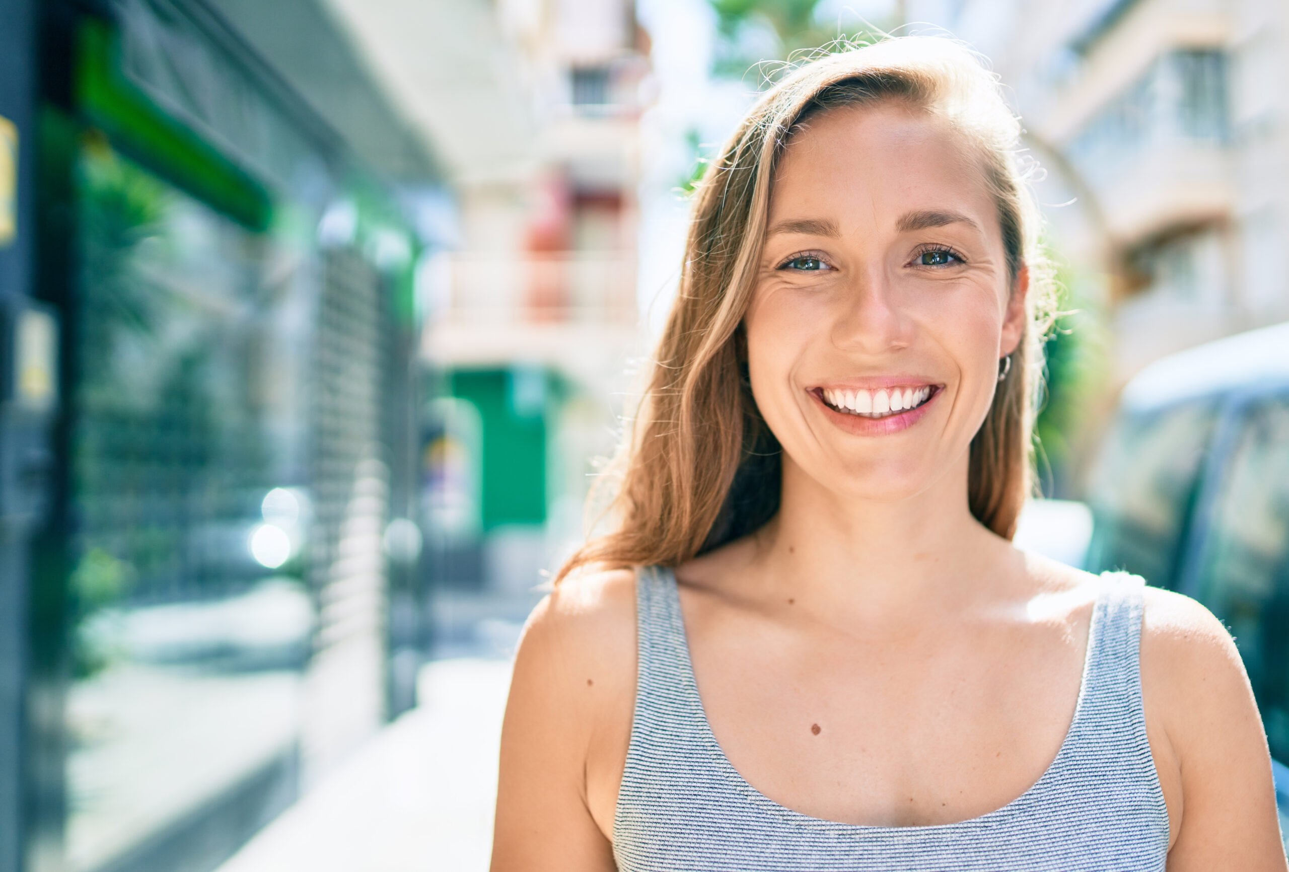 Young blonde woman smiling happy walking the streets of city