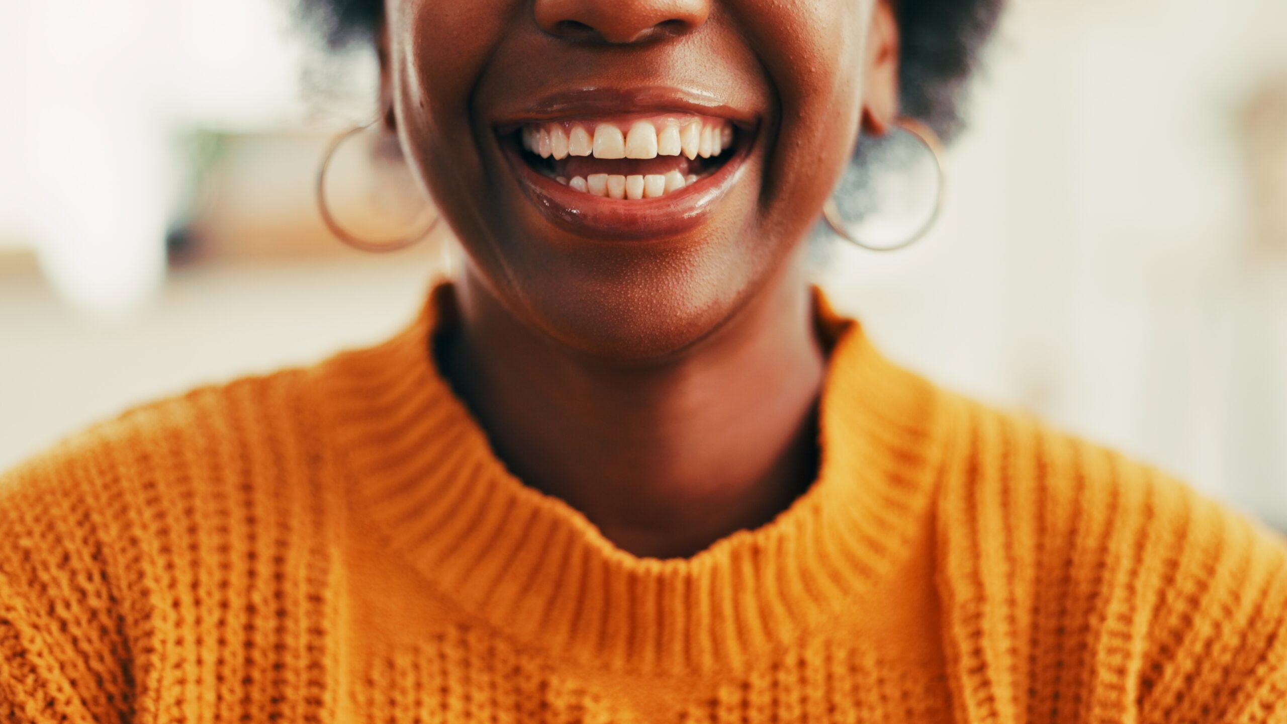 closeup of woman in an orange sweater, perfect white smile