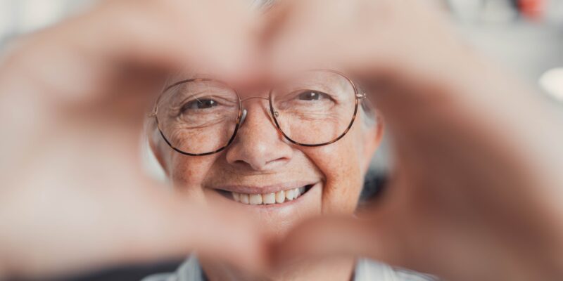 Close-up of an older woman doing a heart sign