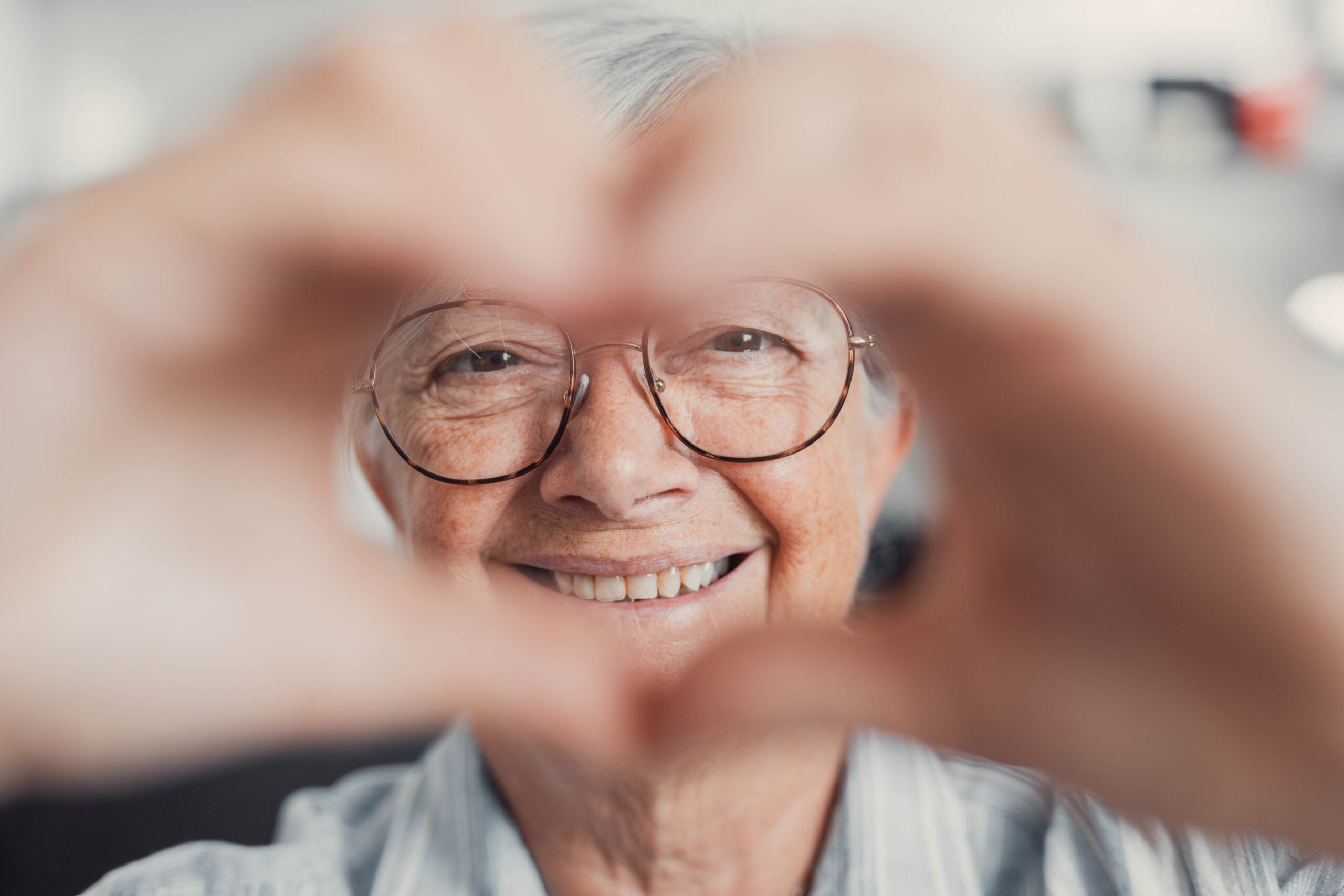 Close-up of an older woman doing a heart sign