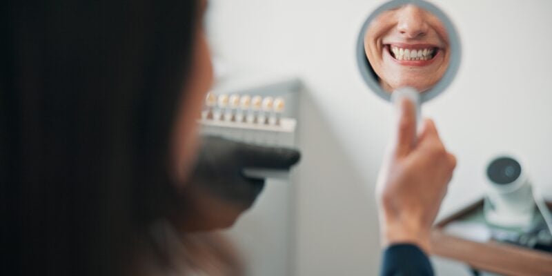 Happy woman, mirror in hand looking at new crown