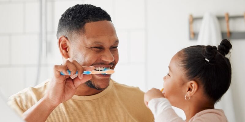 Father, child, and brushing teeth in a bathroom