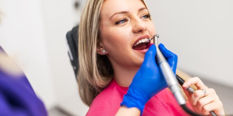 dentist using dental bonding to repair a female patients front tooth